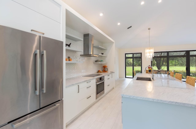 kitchen with white cabinets, sink, wall chimney exhaust hood, appliances with stainless steel finishes, and decorative light fixtures