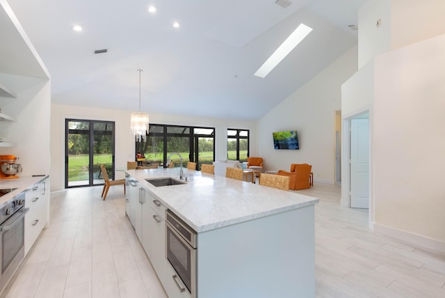 kitchen with high vaulted ceiling, white cabinetry, a healthy amount of sunlight, and sink