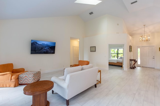 living room with a skylight, high vaulted ceiling, a notable chandelier, and light wood-type flooring