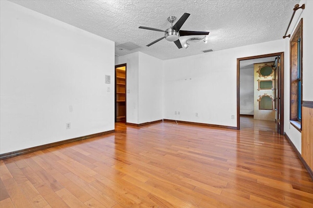 empty room featuring a textured ceiling, light hardwood / wood-style flooring, and ceiling fan