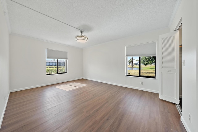 empty room featuring dark hardwood / wood-style floors, crown molding, and a textured ceiling