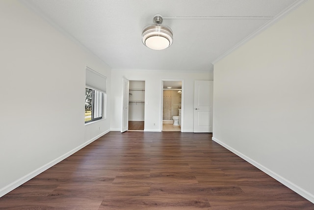 empty room featuring a textured ceiling, dark hardwood / wood-style floors, and ornamental molding