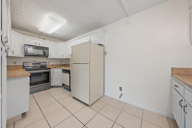 kitchen featuring white cabinets, white appliances, a textured ceiling, and light tile patterned floors