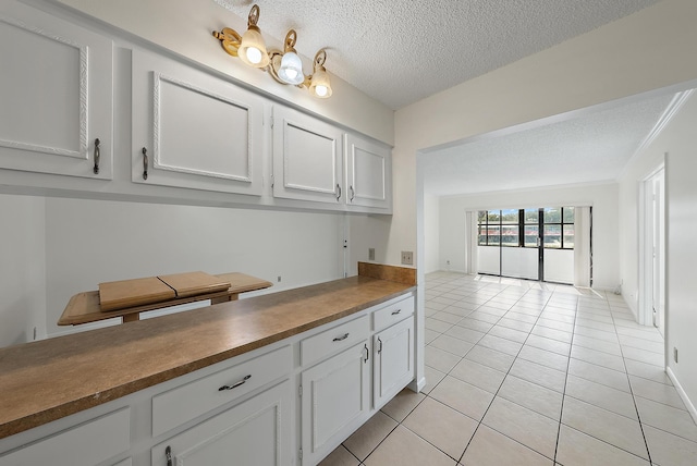 kitchen featuring white cabinets, light tile patterned floors, and a textured ceiling