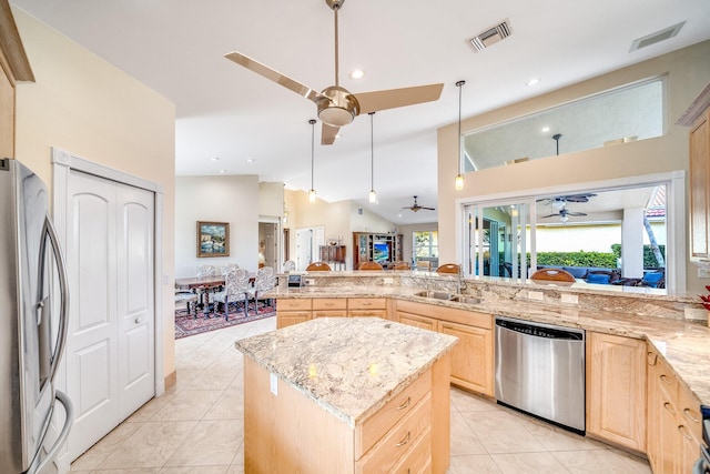 kitchen featuring light brown cabinets, a center island, stainless steel appliances, sink, and vaulted ceiling