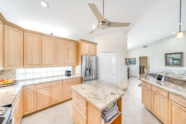 kitchen with a center island, stainless steel appliances, light brown cabinetry, and vaulted ceiling