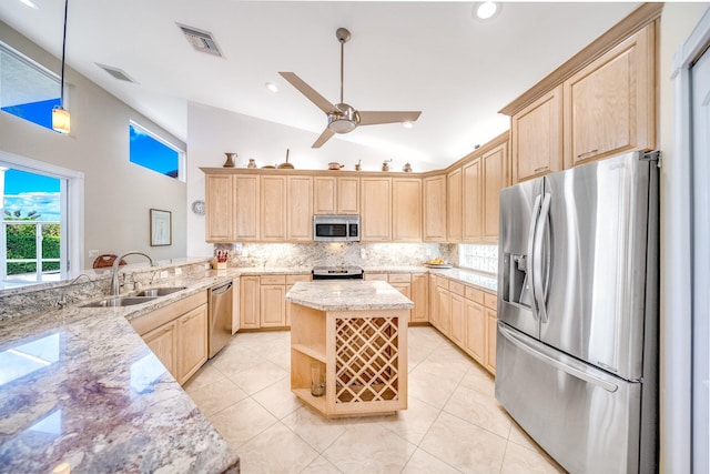 kitchen featuring light stone counters, stainless steel appliances, sink, light brown cabinets, and hanging light fixtures