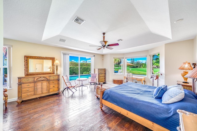 bedroom with ceiling fan, dark wood-type flooring, and a tray ceiling