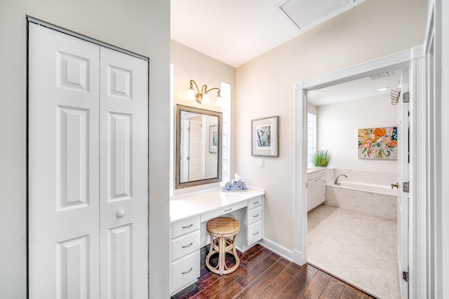 bathroom featuring vanity, a relaxing tiled tub, and hardwood / wood-style flooring