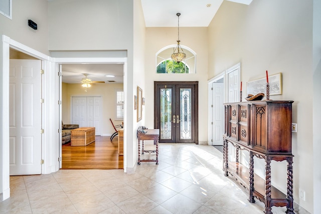 foyer featuring ceiling fan, french doors, a towering ceiling, and light hardwood / wood-style flooring