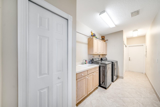 laundry room featuring sink, cabinets, a textured ceiling, light tile patterned floors, and washer and dryer