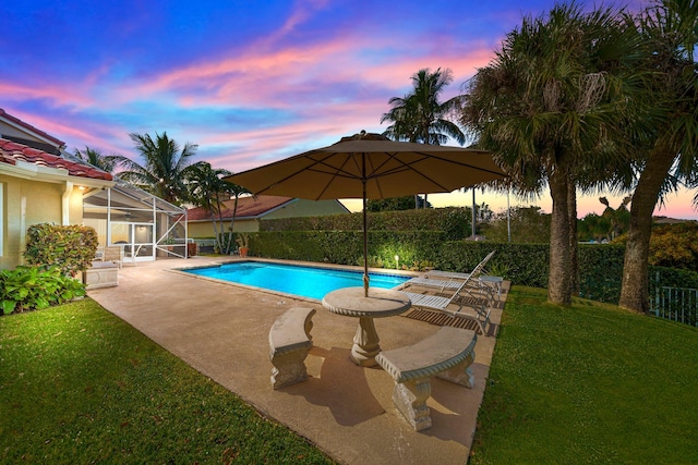 pool at dusk with a yard, a patio area, and a lanai