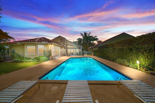 pool at dusk with central AC unit and a patio area