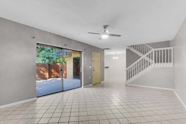 tiled empty room featuring ceiling fan with notable chandelier