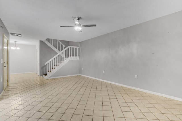 spare room with light tile patterned floors and ceiling fan with notable chandelier