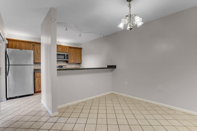 kitchen with hanging light fixtures, stainless steel appliances, tasteful backsplash, kitchen peninsula, and a chandelier