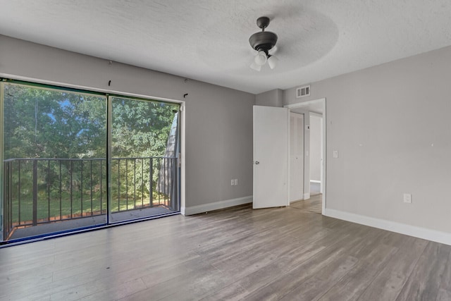 spare room featuring ceiling fan, light wood-type flooring, and a textured ceiling