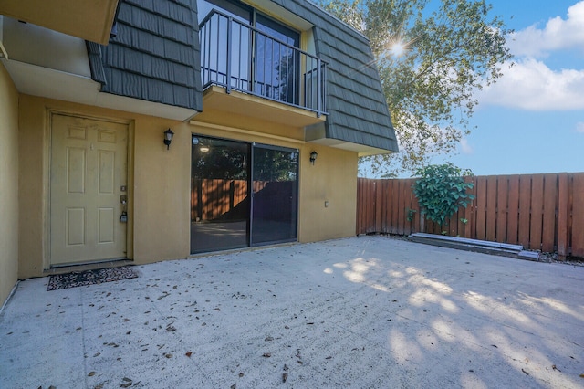 view of exterior entry with a balcony and a patio