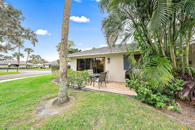 rear view of property featuring a lawn and a patio area