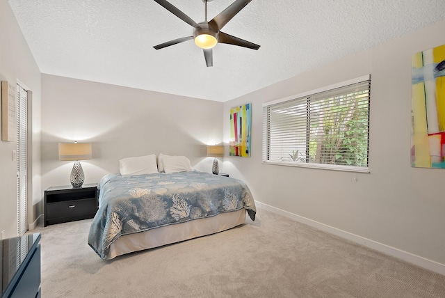 bedroom with a textured ceiling, light colored carpet, and ceiling fan