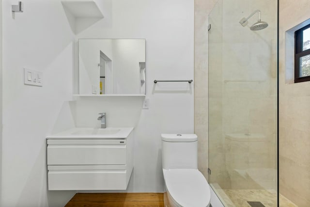 bathroom with a tile shower, vanity, and toilet