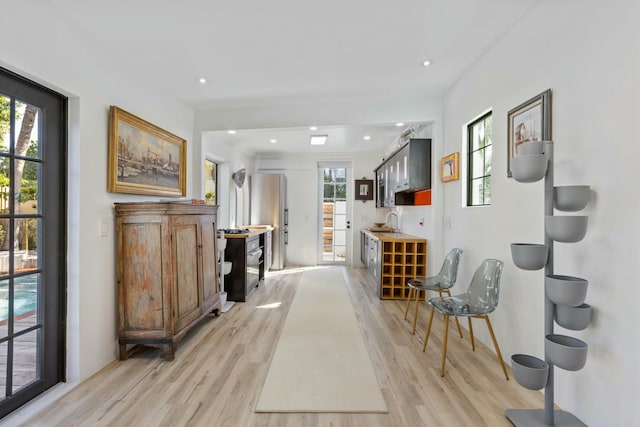 corridor featuring light wood-type flooring and sink