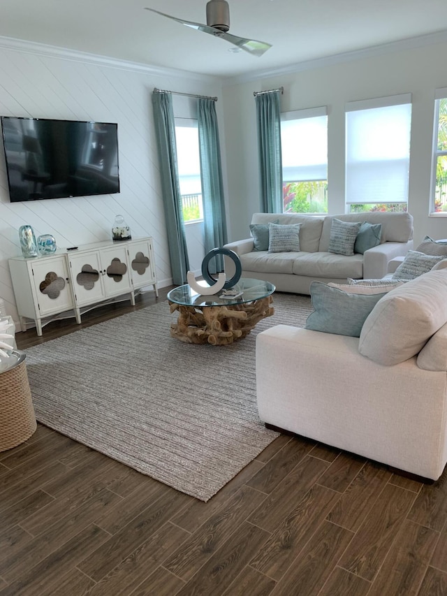 living room with ornamental molding, wooden walls, ceiling fan, and dark wood-type flooring