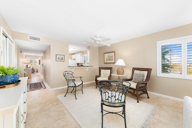 living area with ceiling fan and light tile patterned floors