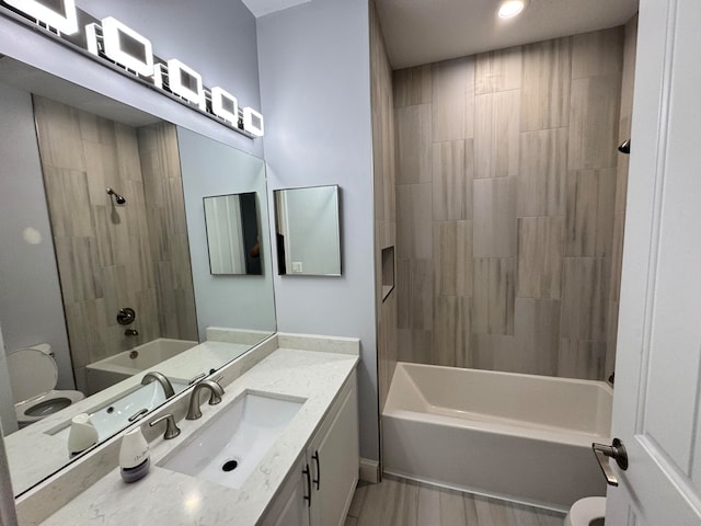 full bathroom featuring vanity, tiled shower / bath combo, and toilet