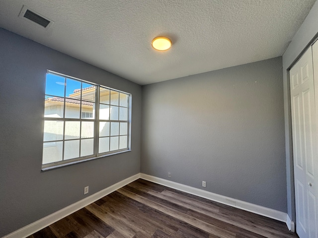 spare room with a textured ceiling and dark wood-type flooring