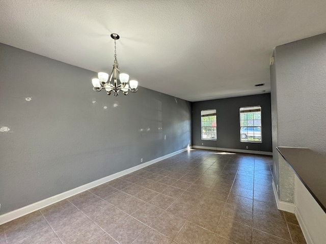 interior space featuring tile patterned flooring, a textured ceiling, and a notable chandelier