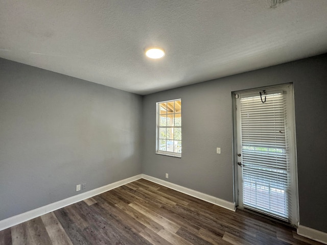 unfurnished room with dark wood-type flooring and a textured ceiling