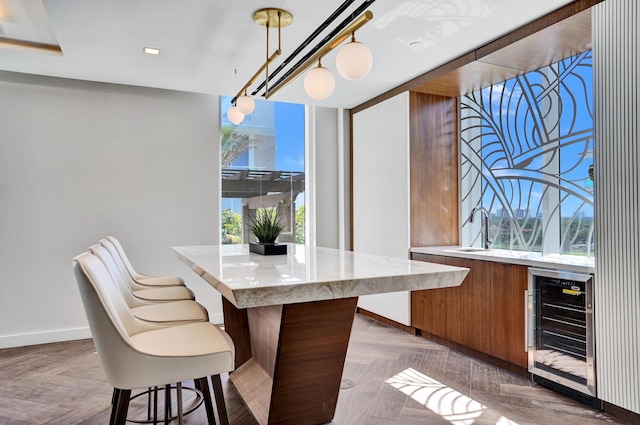 bar featuring pendant lighting, beverage cooler, a sink, and baseboards