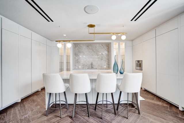 kitchen with tile walls, modern cabinets, white cabinets, and a kitchen breakfast bar