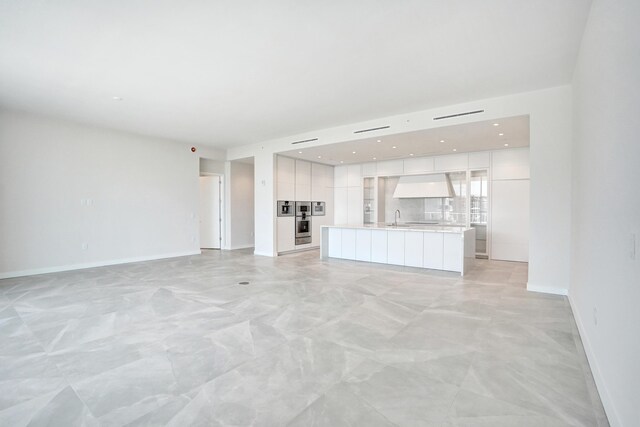 kitchen featuring premium range hood, a sink, white cabinetry, light countertops, and modern cabinets