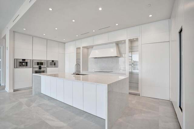 kitchen featuring a sink, white cabinetry, finished concrete flooring, modern cabinets, and custom range hood