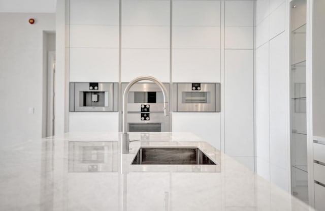 kitchen with modern cabinets, white cabinetry, and light stone countertops