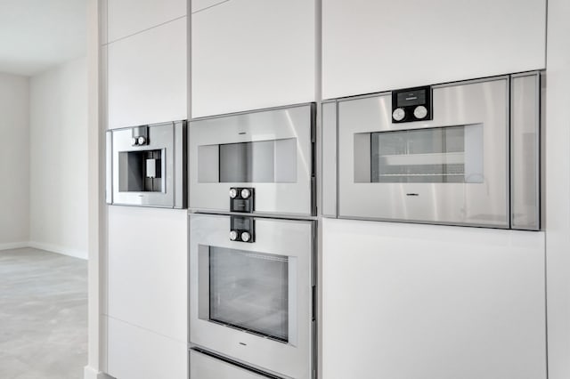 interior details with concrete flooring, white cabinetry, baseboards, and modern cabinets