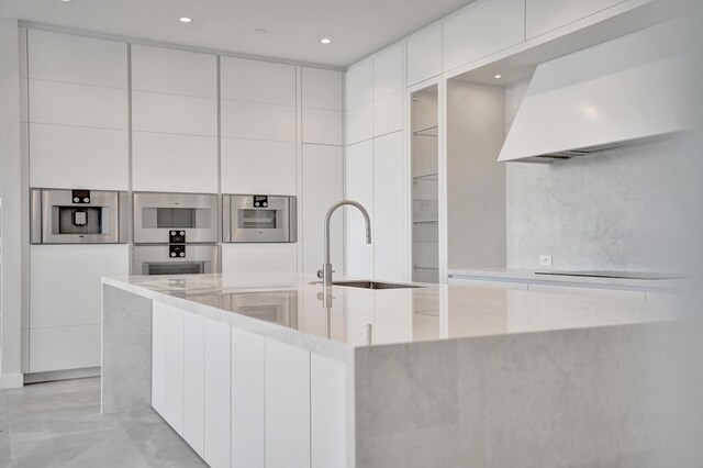 kitchen featuring white cabinetry, modern cabinets, light countertops, and exhaust hood