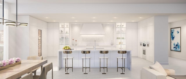 kitchen featuring a kitchen bar, white cabinets, and custom exhaust hood