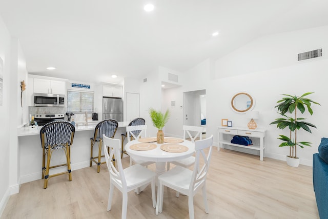 dining room featuring lofted ceiling and light wood-type flooring