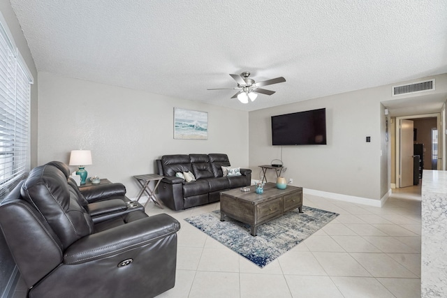 living room featuring ceiling fan, light tile patterned floors, and a textured ceiling