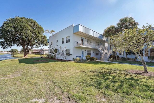 view of front of home with a front lawn and a water view