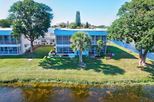 rear view of house featuring a lawn and a water view