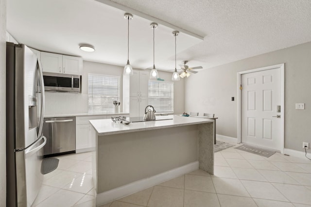 kitchen featuring ceiling fan, stainless steel appliances, light tile patterned floors, a center island with sink, and white cabinets