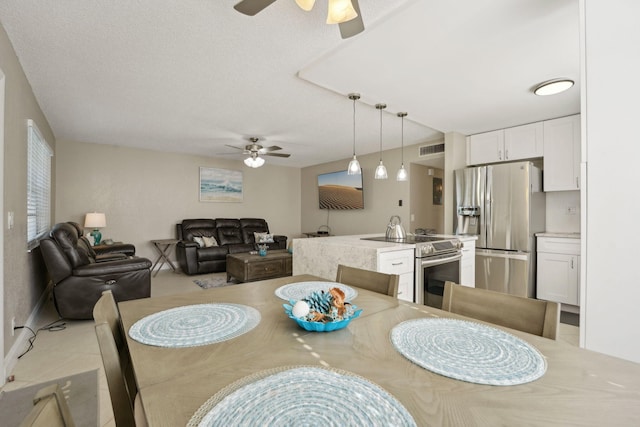 dining area featuring ceiling fan and a textured ceiling