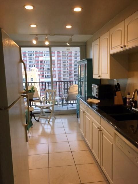 kitchen featuring light tile patterned floors, white appliances, track lighting, and sink