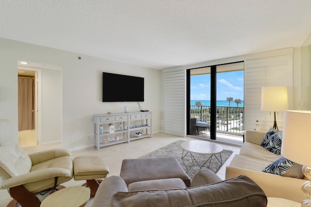 living room featuring floor to ceiling windows, light tile patterned flooring, and a textured ceiling