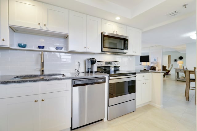 kitchen with sink, stainless steel appliances, tasteful backsplash, white cabinets, and light tile patterned flooring