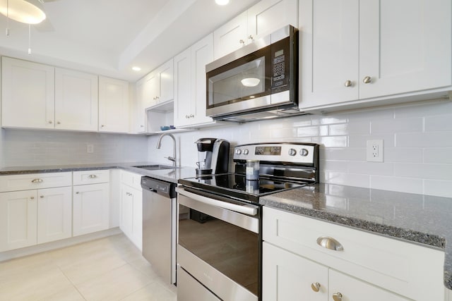 kitchen featuring white cabinetry, sink, backsplash, dark stone countertops, and appliances with stainless steel finishes